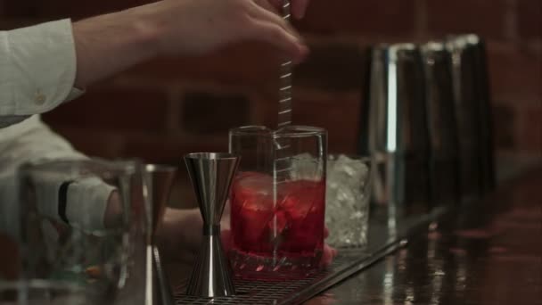 Cantinero profesional en el trabajo en bar mezclando hielo y licor en vidrio para beber — Vídeos de Stock