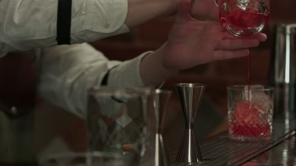 Barman ruce výrobu a zdobení koktejl negroni s plátkem pomeranče — Stock video