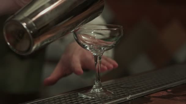 Barman rode alcohol voorbereiding kosmopolitische in champagne glas gieten — Stockvideo