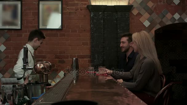 Молоді веселі друзі п'ють коктейлі і розмовляють з барменом у лаунж-барі — стокове відео