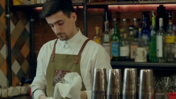 Barman arbeidsongevallen wrijft een glas loking naar een camera — Stockvideo