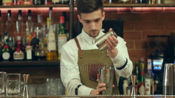 Barman sacudiendo cóctel y verterlo en un vaso vacío en un club nocturno — Vídeos de Stock