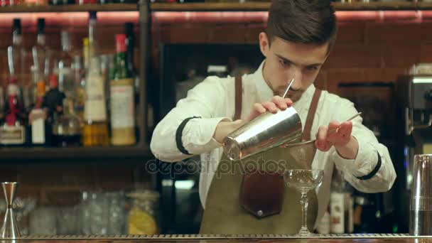 Jonge, bebaarde barman bereiden cocktail drinken met behulp van twee soorten alcohol, zoete siroop in ongewone glas, en het versieren — Stockvideo