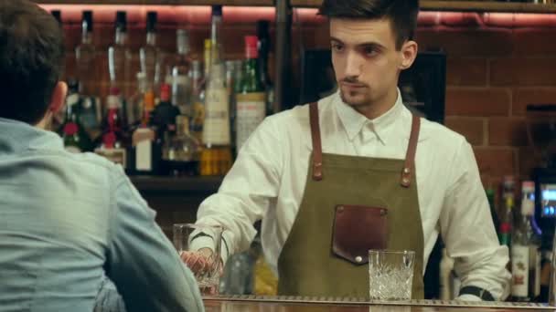 Jonge barman praten en lacht om een mannelijke bezoeker — Stockvideo