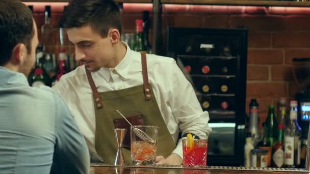 Бармен готовит коктейль для клиента и ждет его реакции — стоковое видео