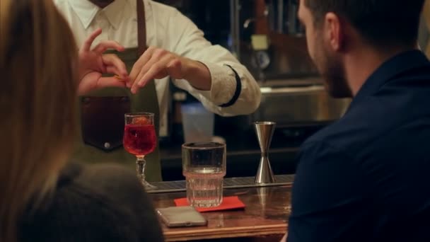 Barman servindo coquetel alcoólico para um homem bonito, ele aplaude com uma bela mulher loira atrás dele — Vídeo de Stock