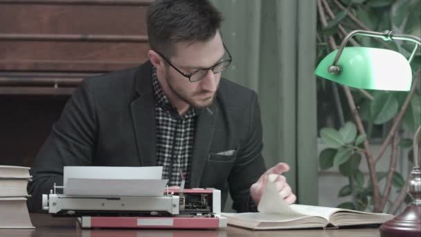 Koncentrerad redaktör kontrollera informationen i boken och skriva på röd vintage skrivmaskin — Stockvideo
