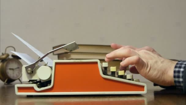 Manos masculinas escribiendo en la vieja máquina de escribir roja en el escritorio con libros — Vídeo de stock
