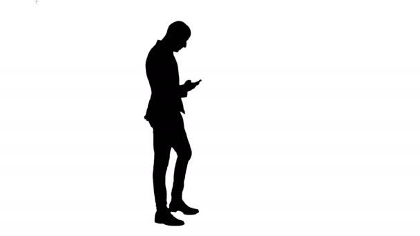 Silhouette affärsman promenader i kontrollera upp sin telefon — Stockvideo