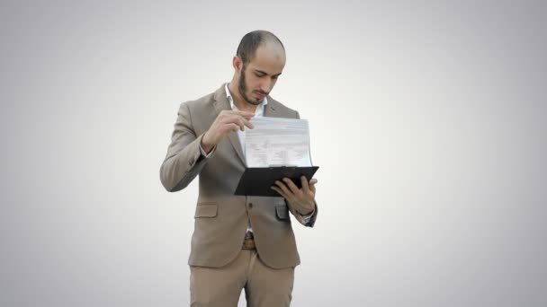 Koncentrerad affärsman läser finansiella rapport på vit bakgrund. — Stockvideo