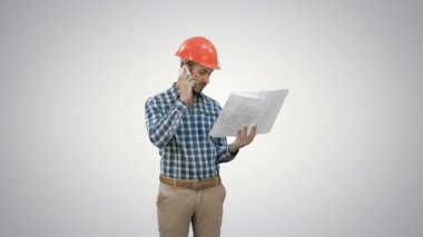 Beyaz arka plan üzerinde planları tutan telefonda konuşurken site yöneticisi.