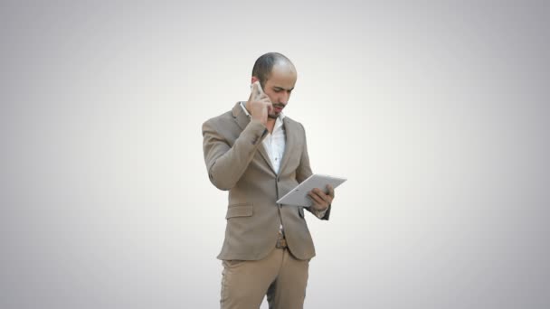 Homme occupé parlant sur téléphone mobile et tenant tablette PC sur fond blanc . — Video