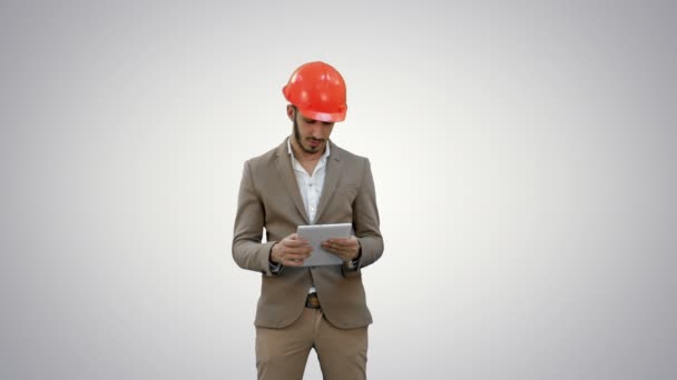 Joven arquitecto en casco sosteniendo la tableta y mostrando el pulgar hacia arriba sobre fondo blanco . — Vídeos de Stock