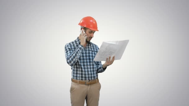 Kierownik budowy, rozmawiać przez telefon trzymając plany na białym tle. — Wideo stockowe