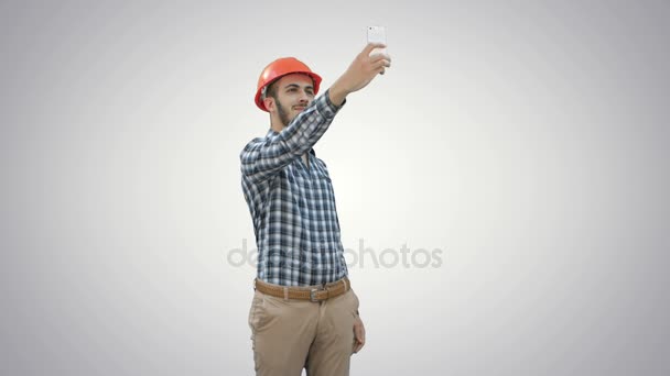 Bouwvakker met behulp van telefoon te nemen van selfies op witte achtergrond. — Stockvideo