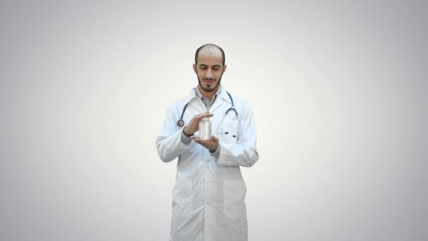 Sorridente medico raccomandando pillole e mostrando un pollice in su su su sfondo bianco . — Video Stock