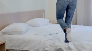 Genç sarışın kadın beyaz otel yatak üzerinde atlama