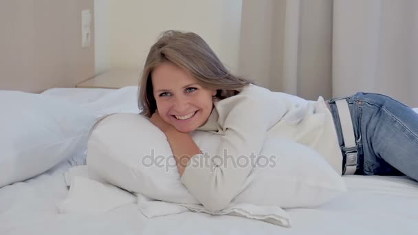 Sorridente giovane donna sdraiata nel letto in camera d'albergo — Video Stock