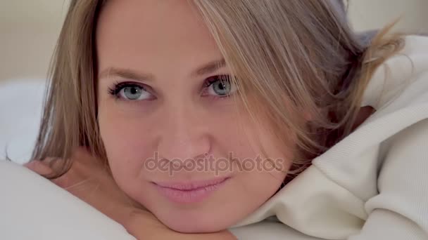 Nette Frau, die auf ihrem Bett liegt und in die Kamera lächelt — Stockvideo