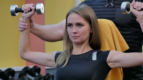 Instructeur personnel aidant l'exercice féminin avec haltères dans la salle de gym — Video