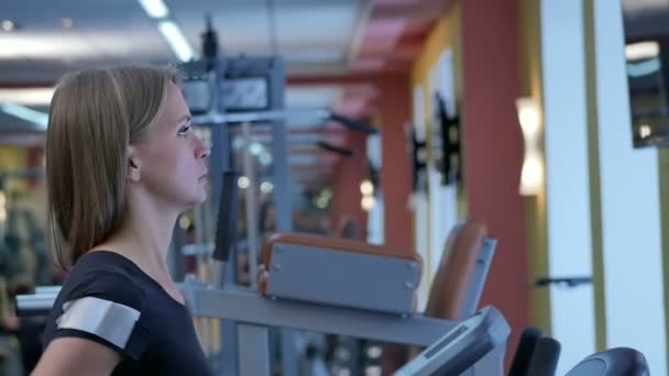 Spor salonunda koşu bandı üzerinde çalışan genç kadın — Stok video