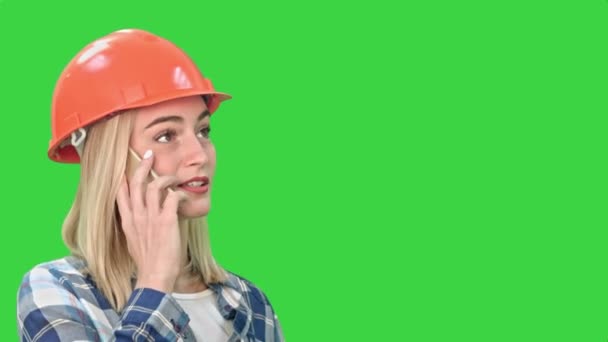 女人在橙色头盔有电话，在绿色屏幕，色度键上讨论对象的问题. — 图库视频影像