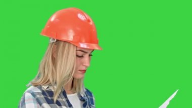 Oldukça genç bir mühendis kadın taslak inceleyerek çözümlenirken düzeni proje tasarım Chroma anahtar yeşil ekran planlıyor..