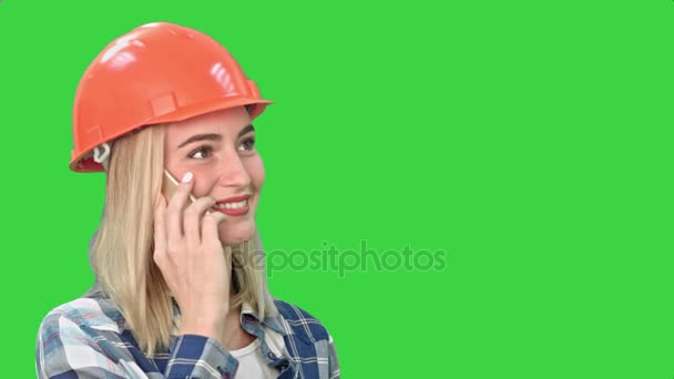 Hermosa mujer feliz en hardhat naranja tienen una llamada telefónica a través de teléfono inteligente y sonriendo en una pantalla verde, Chroma Key . — Vídeo de stock