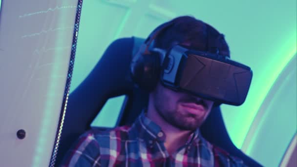 Jovem sentado em cadeira de realidade virtual interativa — Vídeo de Stock