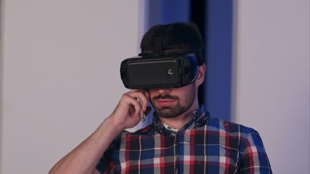 Joven serio en gafas de realidad virtual hablando por teléfono — Vídeos de Stock