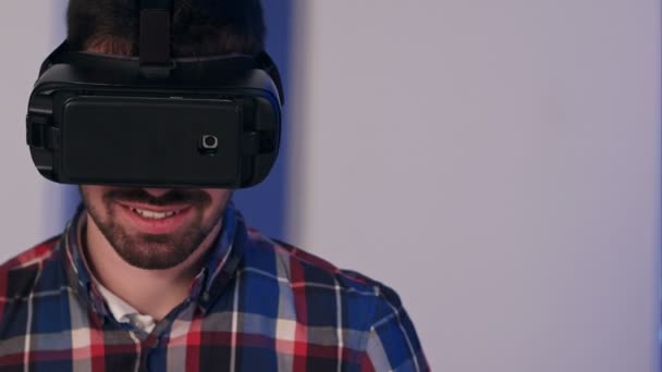 Смолящий человек в VR-очках смотрит в камеру после сеанса виртуальной реальности — стоковое видео