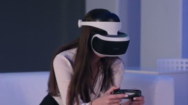 Sanal gerçeklik aygıt giyen ve gamepad ile bilgisayar oyunu oynamak kadın