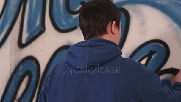 Artista maschio che disegna graffiti su una parete con una bomboletta spray — Video Stock