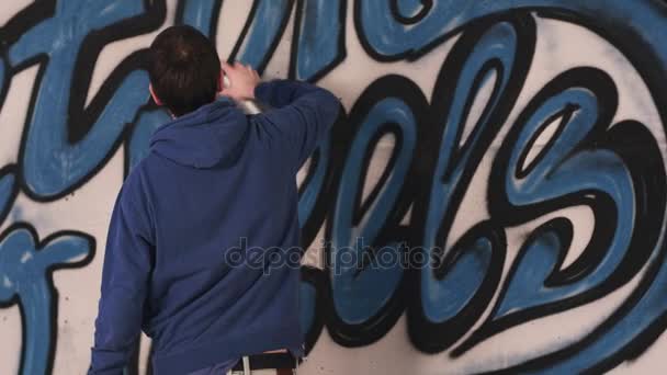 jonge stedelijke schilder tekenen van graffiti op de muur