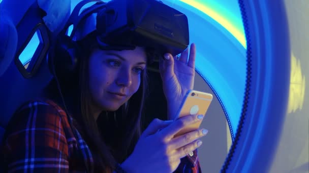 Chica alegre en auriculares de realidad virtual comprobando sus selfies en el teléfono — Vídeo de stock