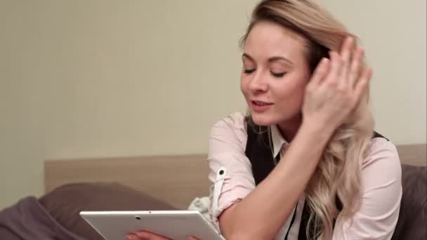 Mulher sorridente excitado ter chamada de vídeo em tablet enquanto sentado em sua cama — Vídeo de Stock