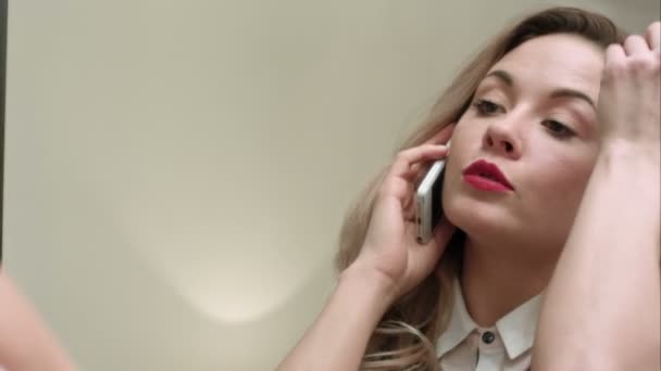 Молодая красивая женщина наносит макияж на лицо кистью, имеет телефонный звонок, опаздывает — стоковое видео