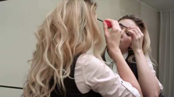 Young beautiful woman applying make up infront of a mirror — Stock Video