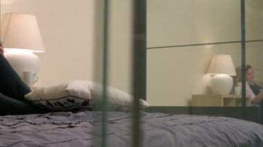 Genç güzel kadın yatakta, Tv kanallarında dönüm yatıyordu ve smartphone evde kullanma