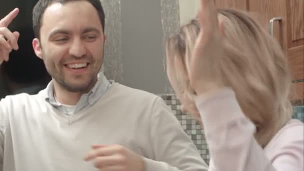 Pareja feliz bailando escuchando música en la cocina en casa — Vídeos de Stock