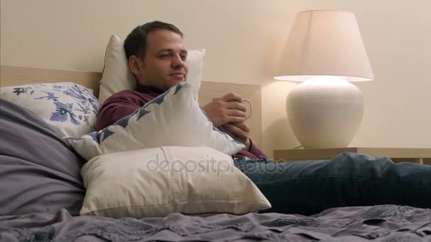 Чоловік дивиться телевізор і п'є чай вночі — стокове відео