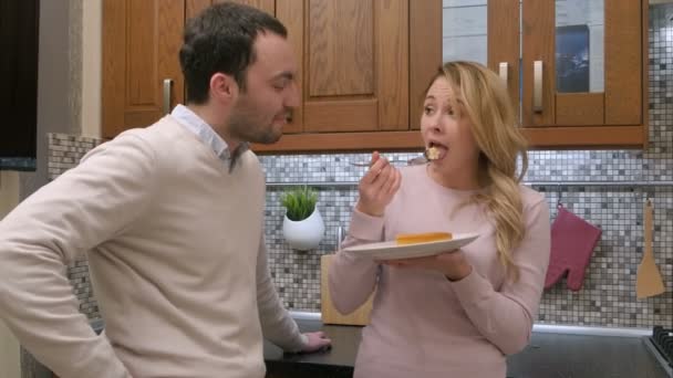 Casal faminto comer bolo delicioso, mulher alimentando o homem, na cozinha em casa — Vídeo de Stock