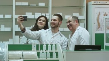 Eczacı ve stajyerler neşeli takım al selfie smartphone ile işyerinde