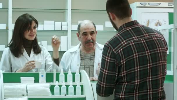 Atrakcyjna kobieta i starszy farmaceuty słuchanie zawiedziony mężczyzna klienta jakości leku i spróbować rozwiązać problem — Wideo stockowe