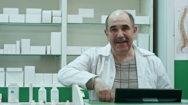 Retrato del farmacéutico senior sonriendo y hablando con una cámara — Vídeos de Stock