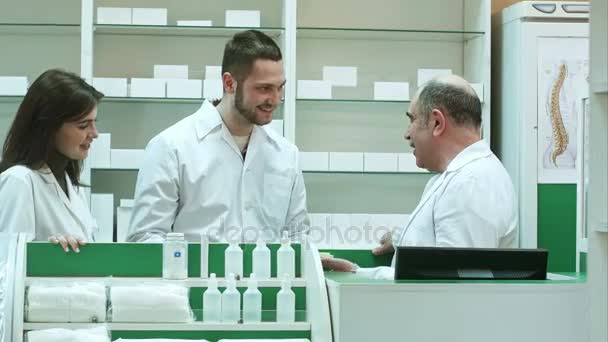 Vriendelijke medische team in laboratoriumjas bespreken nieuwe pillen in apotheek — Stockvideo