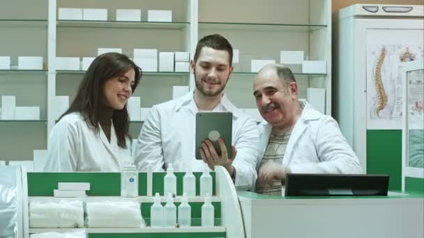 Компетентна команда аптек з фармацевтом та фармацевтами, які мають відеочат з колегами за допомогою цифрового планшета — стокове відео