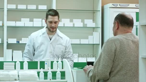 Giovane farmacista e anziano cliente con farmaci e prescrizione in farmacia — Video Stock