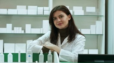 Gülümseyen mutlu kendine güvenen genç kadın eczacı eczane kamera güzel büyük bir sıcak samimi gülümseme veren bir masa üzerine eğilerek