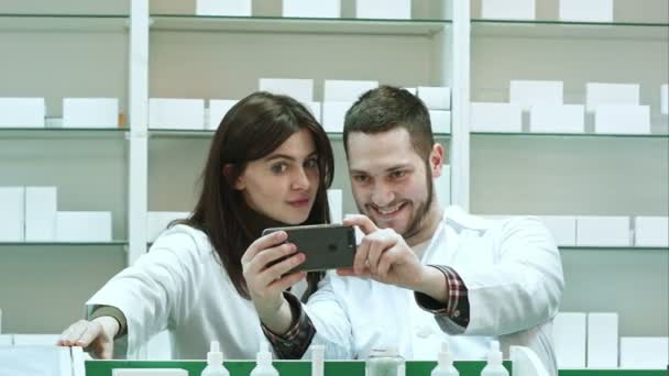 Sonriendo dos farmacéuticos tomando selfie en farmacia — Vídeo de stock